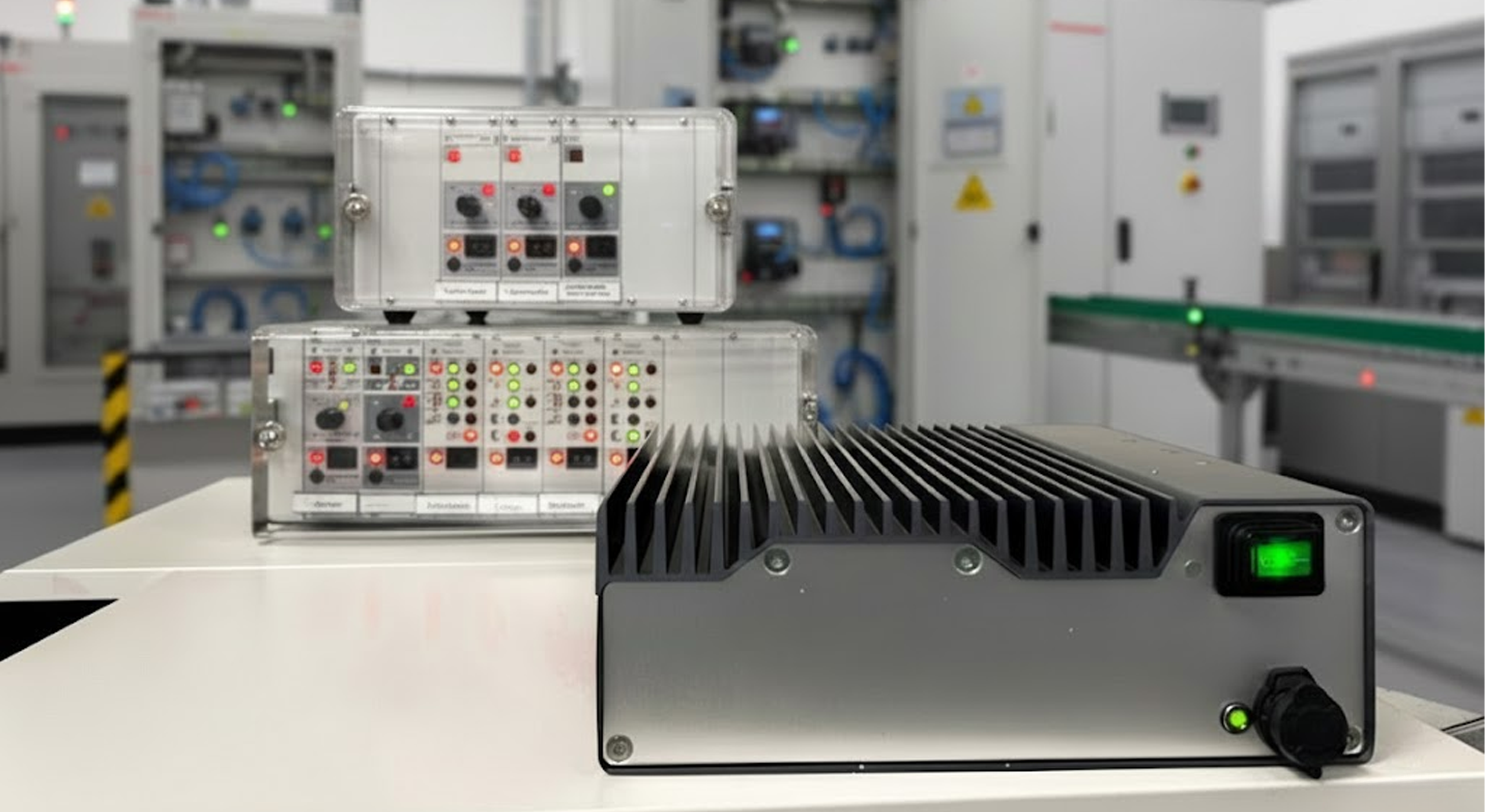 MOBADRIVE FC 3082 frequency controller displayed in the foreground of a production environment, with older Schmocker SE-series control units stacked behind it, illustrating the evolution from legacy feeder controllers to the new MOBADRIVE generation.